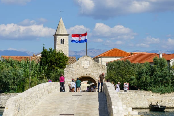 Stone bridge and gate leading into Nin, with a church bell tower