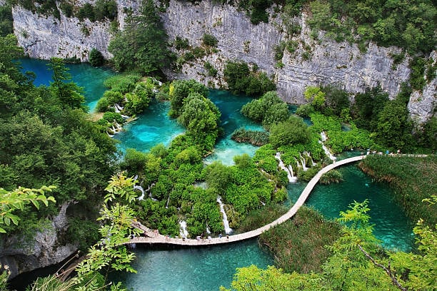 Tirkizna jezera i vijugava staza ispod stijena na Plitvicama