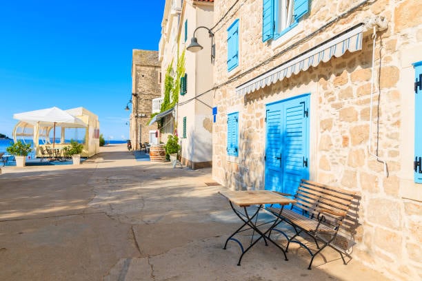 Stone street with blue shutters by the sea in Primošten